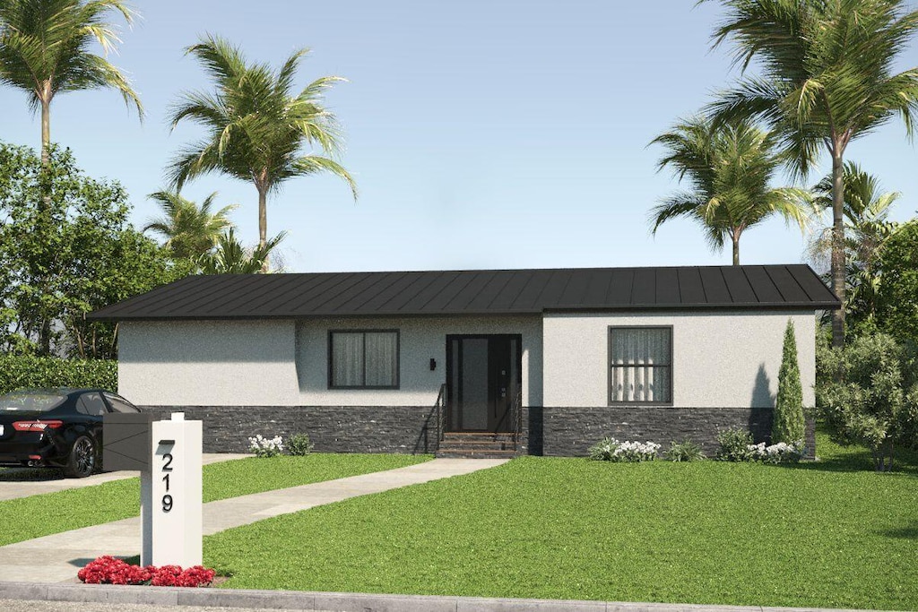 219 32nd St, West Palm Beach, FL 33407 - view of front of property with stone siding, stucco siding, a standing seam roof, a front yard, and metal roof