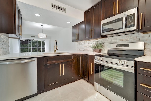 kitchen featuring appliances with stainless steel finishes, decorative light fixtures, tasteful backsplash, sink, and dark brown cabinetry