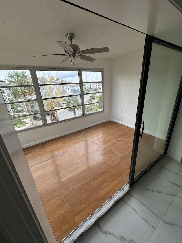 unfurnished sunroom with ceiling fan