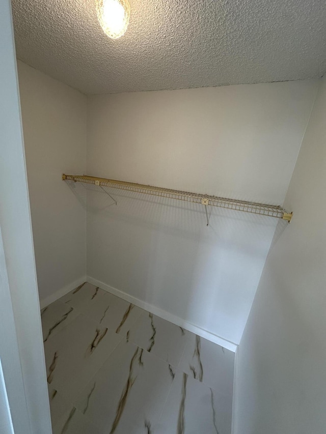 walk in closet featuring marble finish floor