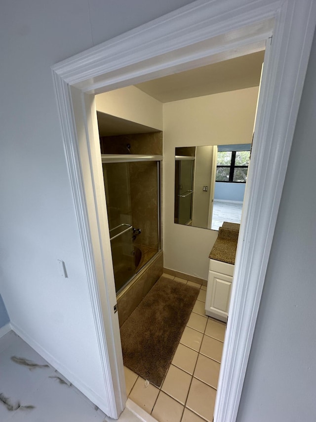 bathroom with tile patterned floors, baseboards, vanity, and combined bath / shower with glass door