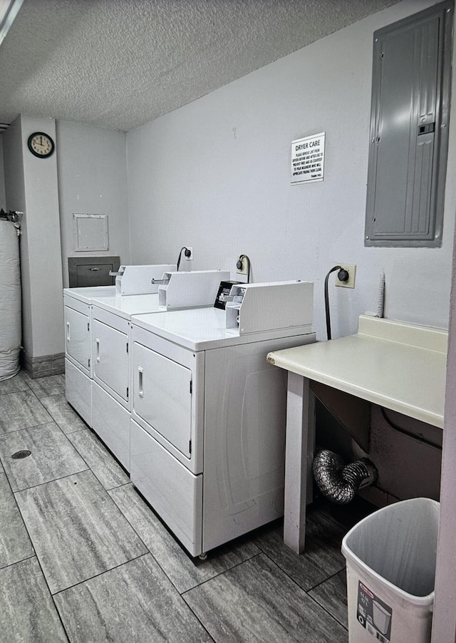 common laundry area featuring washer and dryer, wood finish floors, electric panel, and a textured ceiling