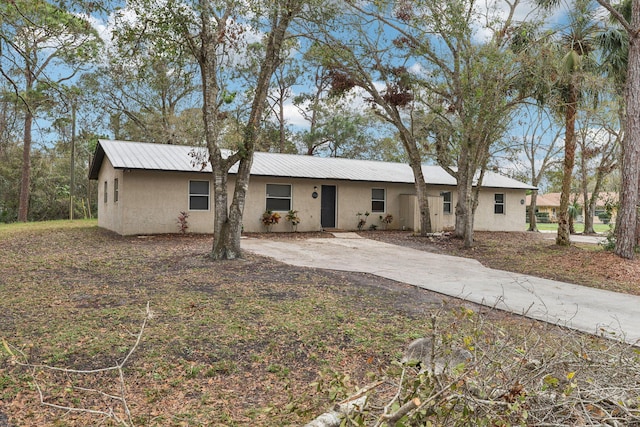 ranch-style house featuring metal roof and stucco siding