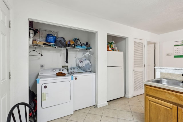 clothes washing area featuring light tile patterned floors, a sink, a textured ceiling, laundry area, and independent washer and dryer