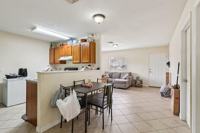 dining space featuring light tile patterned floors, baseboards, a textured ceiling, and washer / dryer