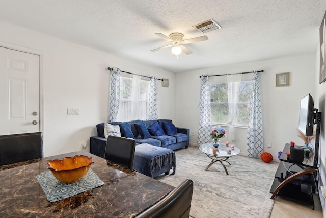 living area with ceiling fan, a textured ceiling, visible vents, and a wealth of natural light