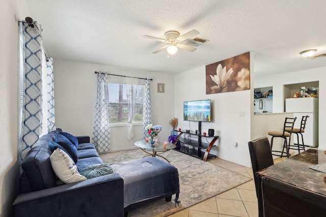 living area with light tile patterned floors, ceiling fan, a textured ceiling, and visible vents