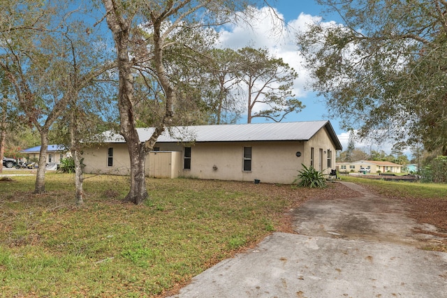 view of front of property with metal roof, a front lawn, and stucco siding