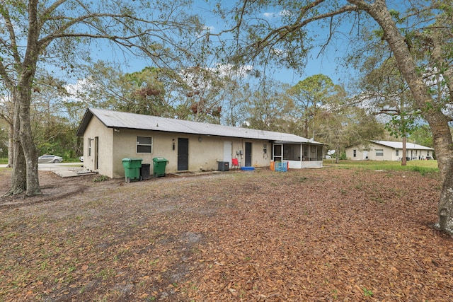 rear view of property featuring central AC, a sunroom, and stucco siding