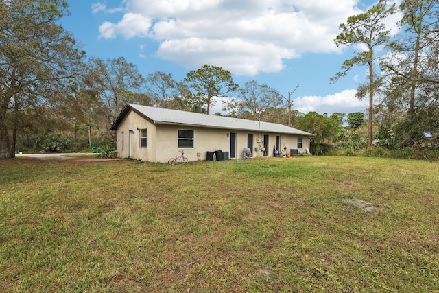 back of property featuring a lawn and stucco siding