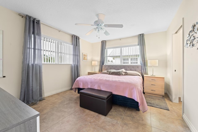 bedroom with light tile patterned floors, baseboards, a ceiling fan, and a textured ceiling