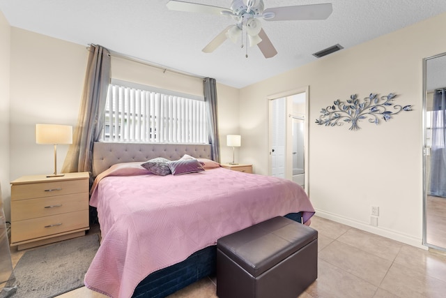 bedroom featuring baseboards, visible vents, a ceiling fan, a textured ceiling, and light tile patterned flooring