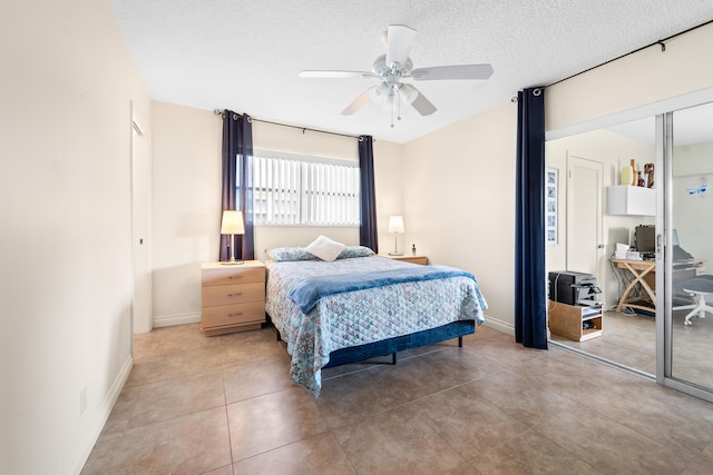 tiled bedroom with a ceiling fan, a textured ceiling, and baseboards