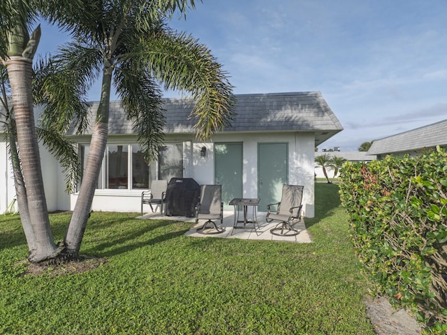 back of property featuring a yard, a shingled roof, mansard roof, and stucco siding