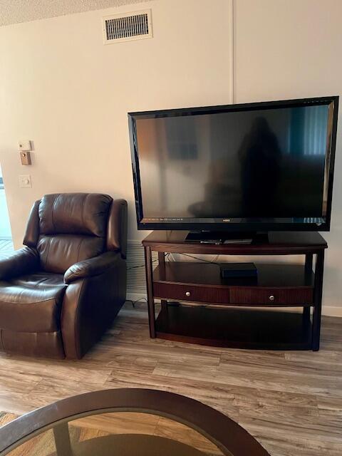 living area featuring visible vents and wood finished floors