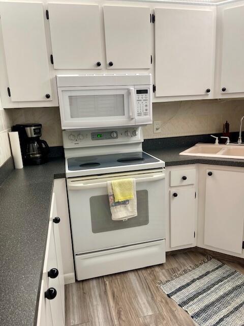 kitchen with dark countertops, white appliances, and white cabinets