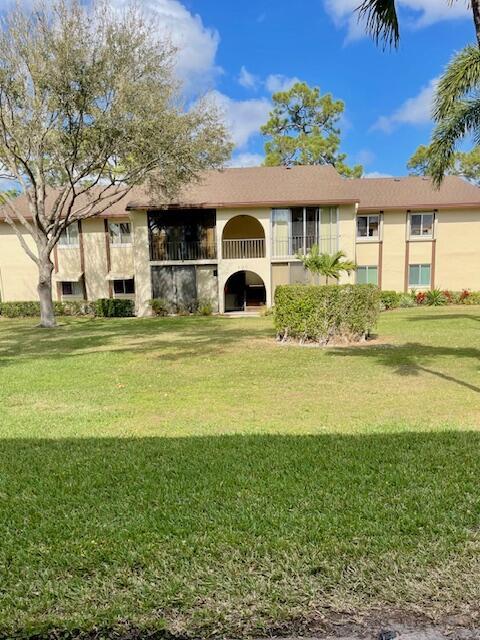 rear view of property with a lawn and stucco siding