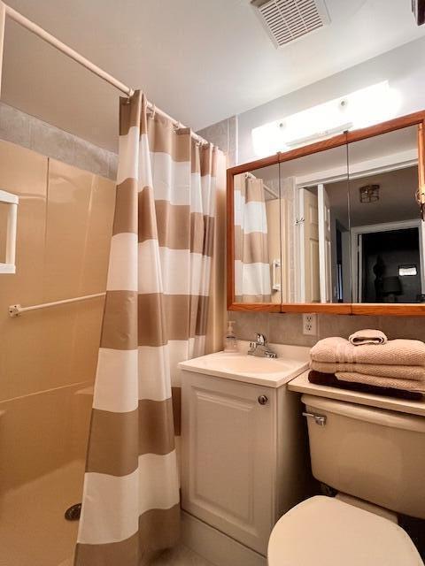 bathroom with visible vents, a shower stall, toilet, and vanity