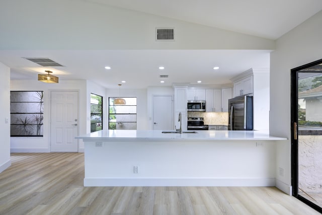 kitchen featuring stainless steel appliances, light countertops, a peninsula, and white cabinetry