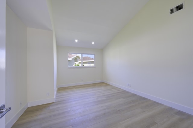 spare room with lofted ceiling, light wood-style flooring, recessed lighting, visible vents, and baseboards