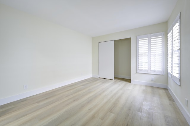 unfurnished bedroom with light wood finished floors, a closet, and baseboards