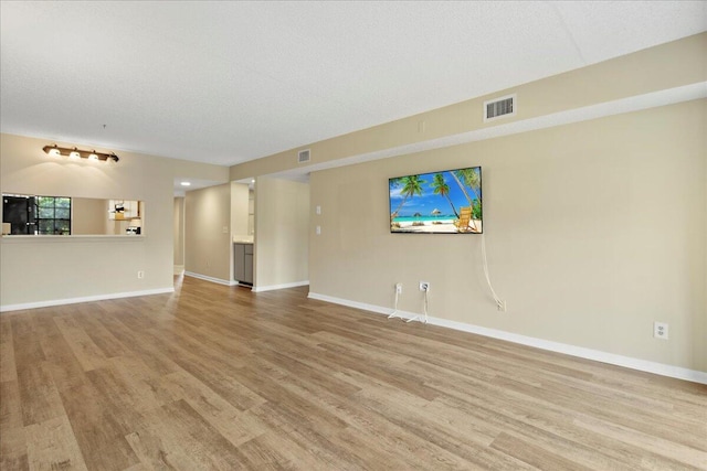 unfurnished living room featuring light wood-style floors, baseboards, and visible vents