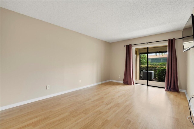 unfurnished room with light wood-style flooring, baseboards, and a textured ceiling