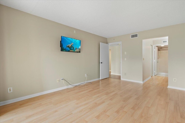 unfurnished bedroom featuring baseboards, light wood-style flooring, visible vents, and a textured ceiling