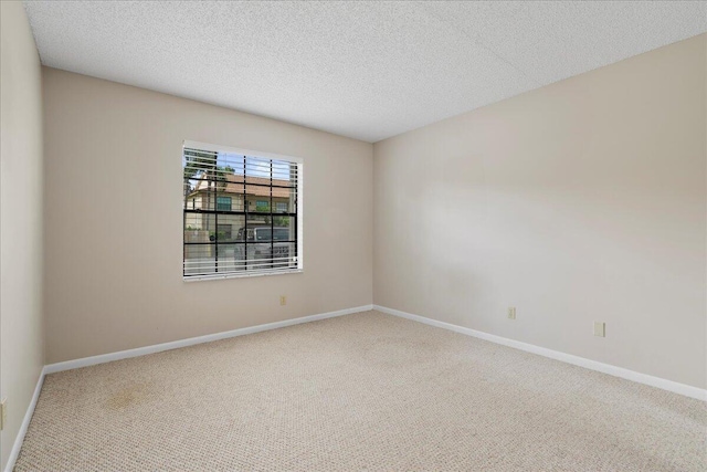 carpeted empty room featuring baseboards and a textured ceiling