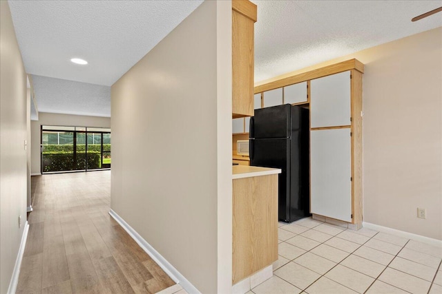 kitchen featuring light tile patterned floors, light countertops, freestanding refrigerator, a textured ceiling, and baseboards