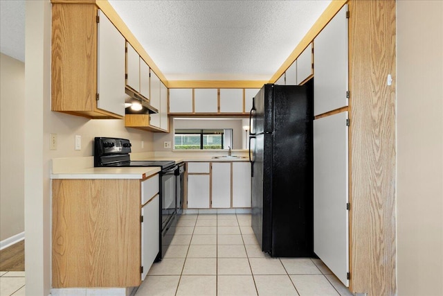 kitchen with black appliances, light tile patterned floors, a sink, and a textured ceiling