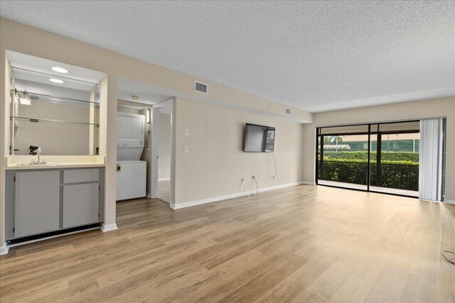 spare room with a textured ceiling, light wood-type flooring, visible vents, and baseboards