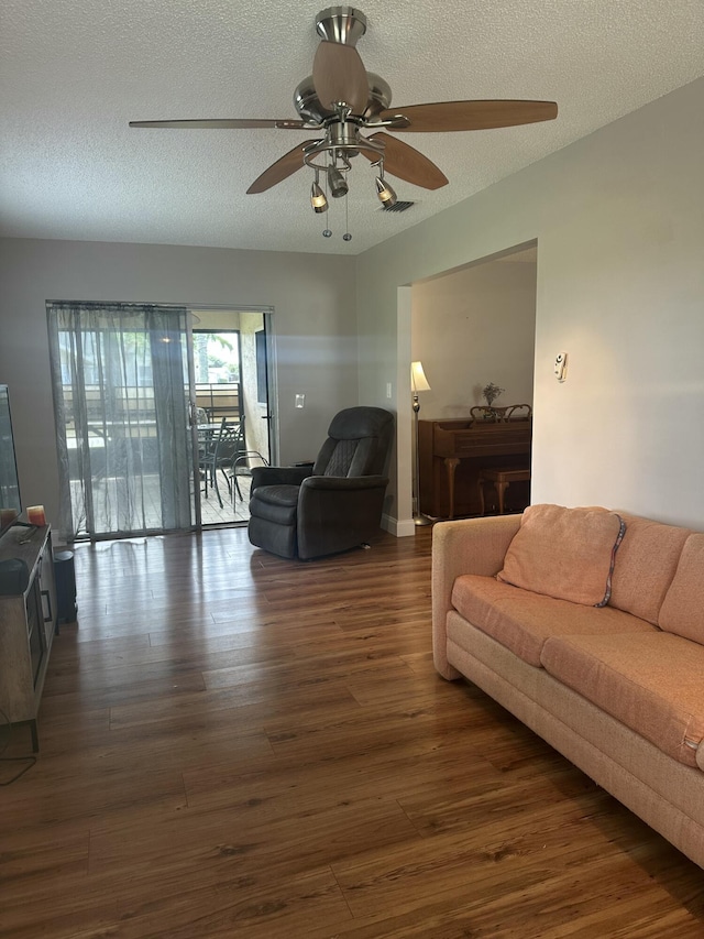 living room featuring dark hardwood / wood-style flooring, ceiling fan, and a textured ceiling