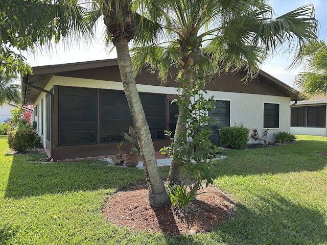 3482 Amalfi Dr, West Palm Beach, FL 33417 - view of property exterior with a sunroom, a lawn, and stucco siding