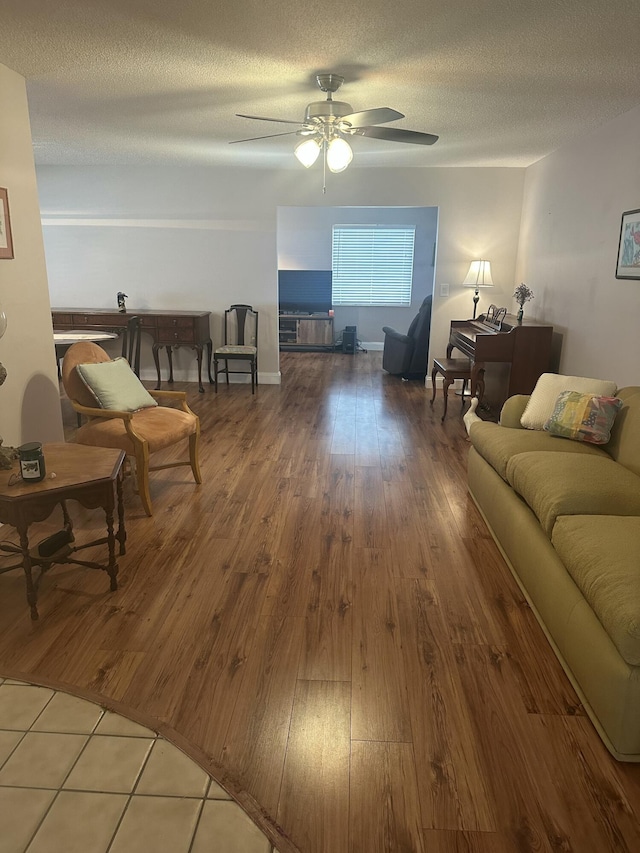 living room featuring wood-type flooring, ceiling fan, and a textured ceiling