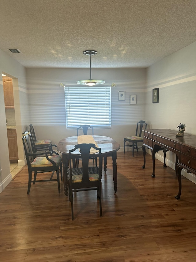 dining room featuring dark hardwood / wood-style flooring and a textured ceiling