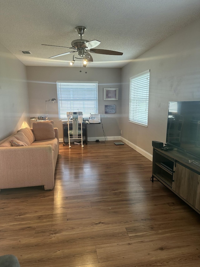 living room featuring ceiling fan, dark hardwood / wood-style floors, and a textured ceiling