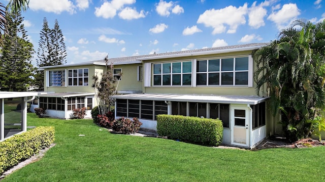 rear view of property with a yard and a sunroom