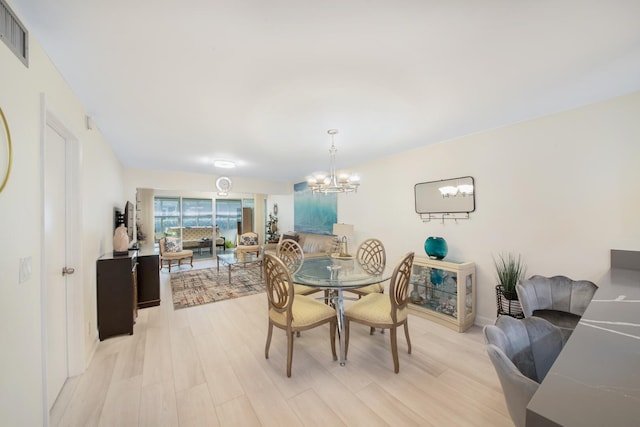 dining area with a chandelier, light wood finished floors, and visible vents