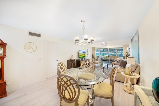 dining area featuring light wood-style floors, baseboards, visible vents, and a chandelier