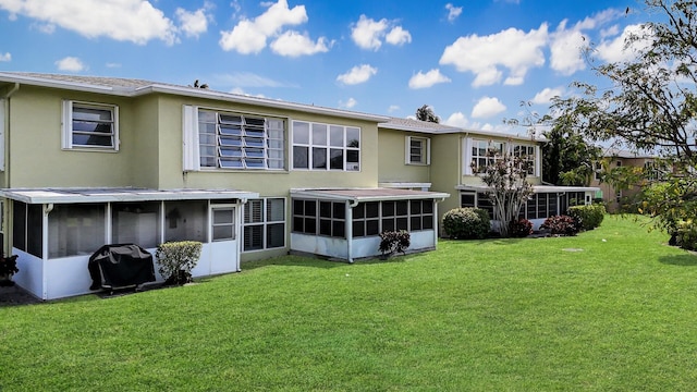 rear view of property with a lawn and a sunroom