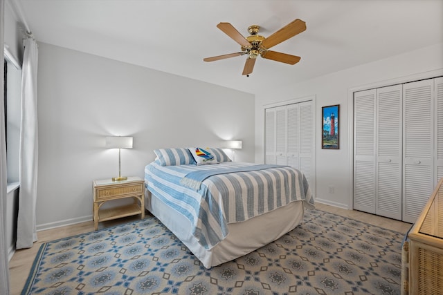 bedroom featuring a ceiling fan, baseboards, and multiple closets