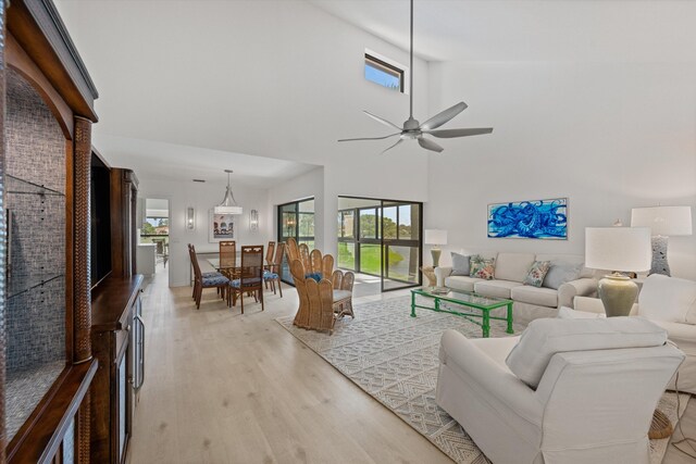 living room featuring light wood-style floors, a healthy amount of sunlight, ceiling fan, and a high ceiling