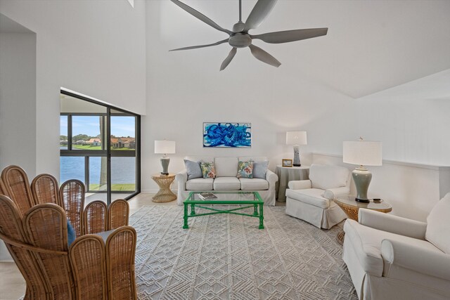 living room with a water view, ceiling fan, and a high ceiling