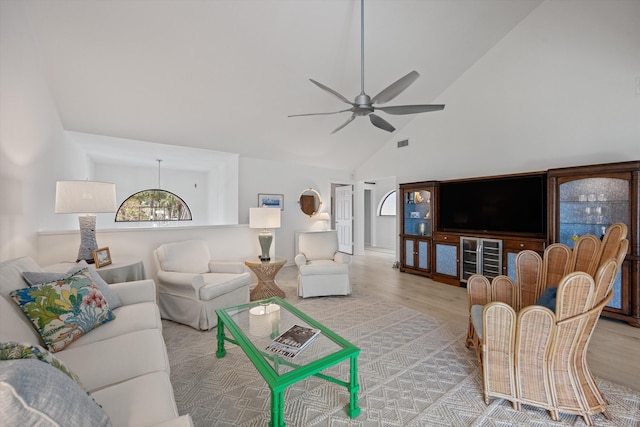 living room featuring light wood-style floors, visible vents, high vaulted ceiling, and ceiling fan with notable chandelier