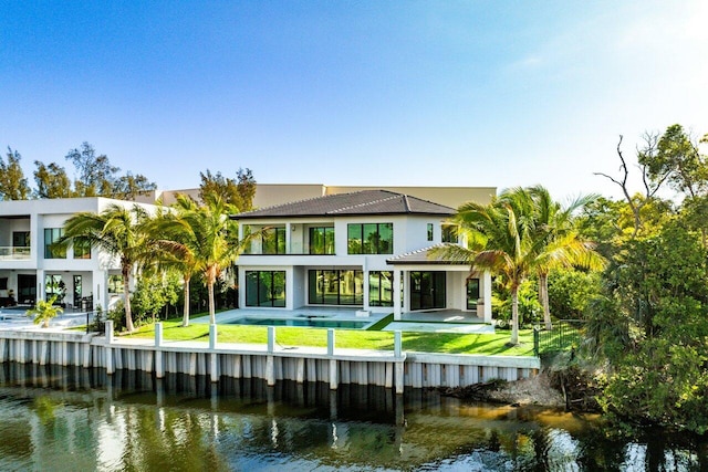 rear view of property featuring a yard, a water view, and a balcony