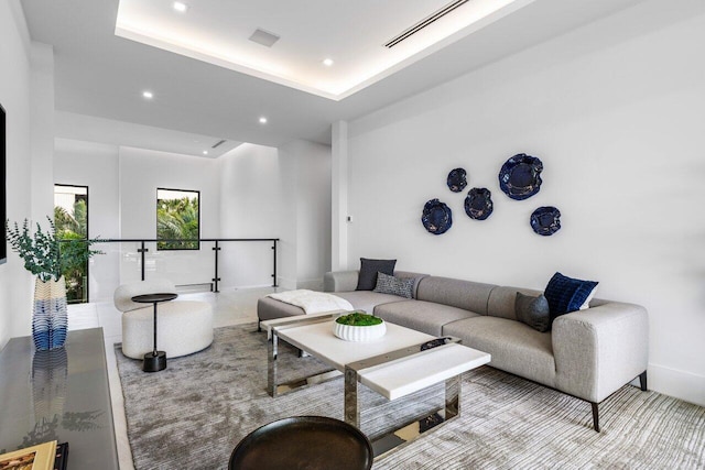 living room featuring a raised ceiling, visible vents, and recessed lighting