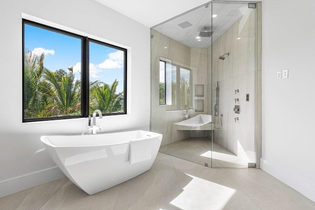 bathroom with a stall shower, a freestanding tub, and baseboards