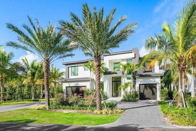 view of front of home with decorative driveway, an attached garage, and stucco siding