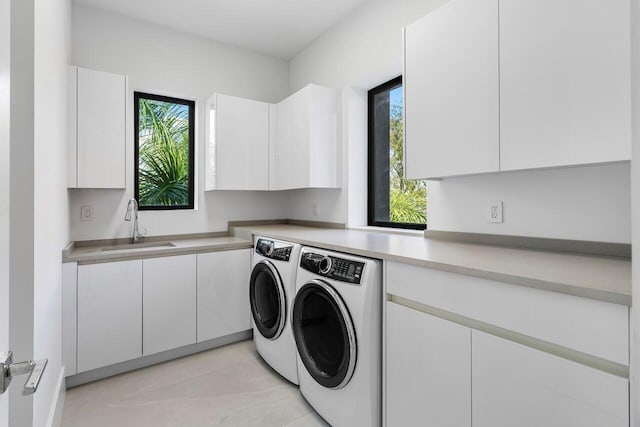 washroom with a sink, cabinet space, washing machine and dryer, and a wealth of natural light